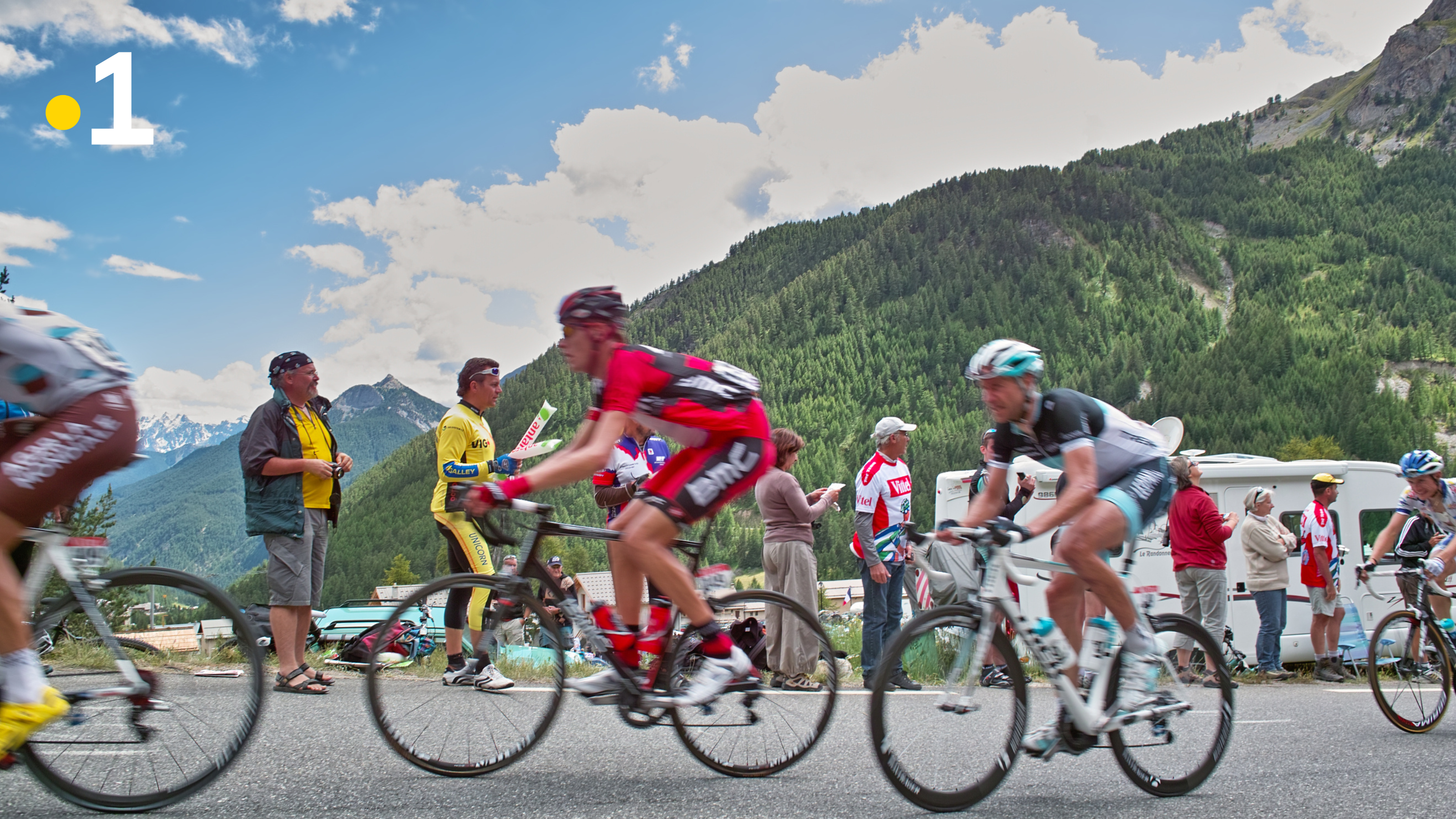 photo cyclistes qui passent en vitesse devant un group de supporters