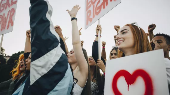 Getty Images/Maskot Low angle view of smiling women protesting with banners in city