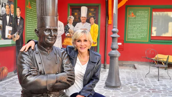 Odile Mattéi devant la statue du chef étoilé Paul Bocuse