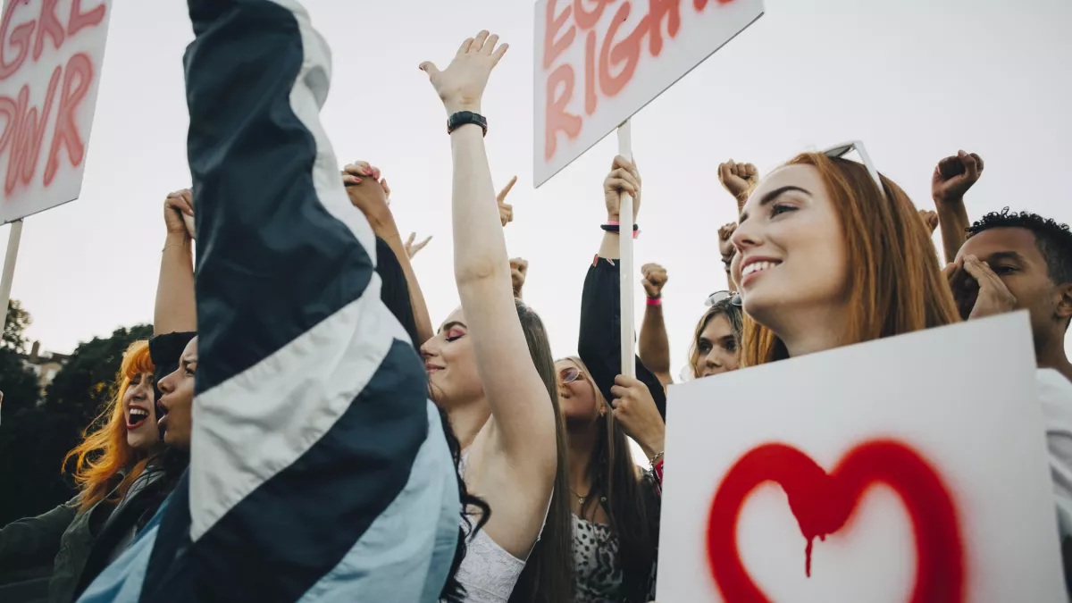 Getty Images/Maskot Low angle view of smiling women protesting with banners in city