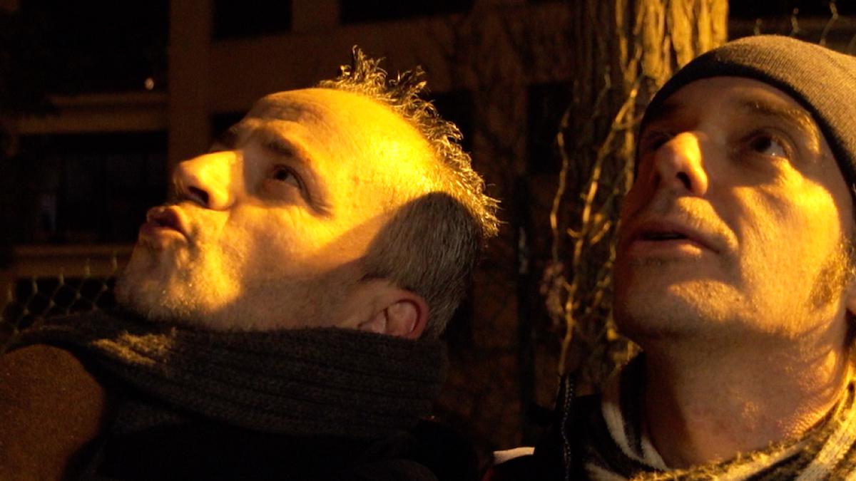 Deux hommes dans la rue, la nuit, sous un réverbère