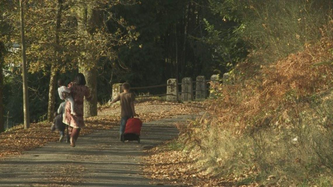 Femme avec ses enfants sur la route de dos avec valises