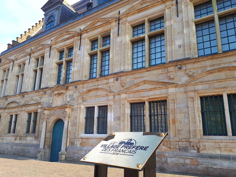 La plaque "Le Village préféré des Français 2018" devant la façade d'un batiment à Cassel