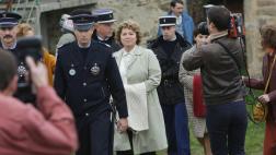 Simone Weber (Véronique Genest) entourée des policiers et des médias après que sa maison de campagne ait été fouillée