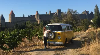 Emilie Broussouloux avec un combi avec des vignes autour et la cité de Carcassonne en fond