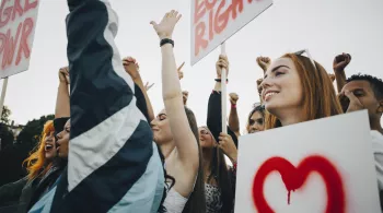 Low angle view of smiling women protesting with banners in city