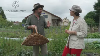La présentatrice de l'émission Courants d'Est, Carine Aigon, est avec un homme qui tient un panier en osier dans un champ de fleurs