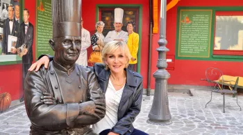 Odile Mattéi devant la statue du chef étoilé Paul Bocuse 