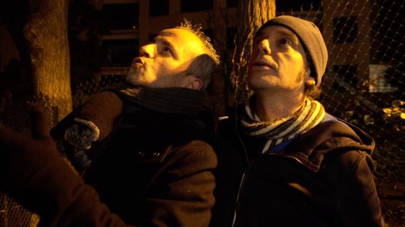 Deux hommes dans la rue, la nuit, sous un réverbère